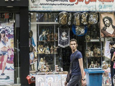 Un homme passe devant une boutique d'objets et de bibelots religieux, dans le quartier de la Choubra, le 11 avril 2017 au Caire, en Egypte - KHALED DESOUKI [AFP]
