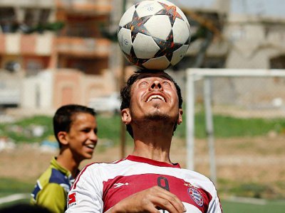 Un joueur de foot irakien portant le maillot du Bayern Munich tient le ballon en équilibre sur son front, avant un match à Mossoul, le 7 avril 2017 - AHMAD GHARABLI [AFP]