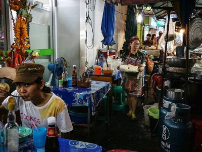 Une cliente mange dans un stand de nourriture, le 17 avril 2017 à Bangkok - LILLIAN SUWANRUMPHA [AFP]