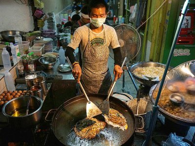 Un vendeur de rue en train de cuisiner, le 17 avril 2017 à Bangkok - LILLIAN SUWANRUMPHA [AFP]