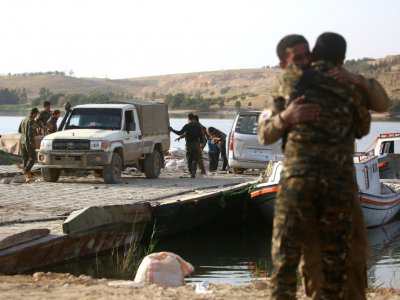 Des combattants arabes syriens se saluent, au bord du lac artificiel Assad à Tabqa (nord) et qui sert actuellement de corridor fluvial, le 29 avril 2017 - DELIL SOULEIMAN [AFP]