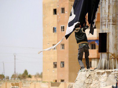 Un membre des forces démocratiques syriennes enlève un drapeau du groupe d'État islamique dans la ville de Tabqa, à environ 55 kilomètres (35 milles) à l'ouest de Raqa, 30 avril 2017 - DELIL SOULEIMAN [AFP]