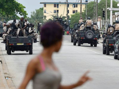 Une femme regarde les soldats ivoiriens qui patrouillent près du quartier général de l'armée, le camp militaire de Gallieni, à Abidjan le 12 mai 2017 - ISSOUF SANOGO [AFP]