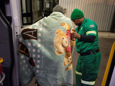 Un ambulancier aide un patient à sortir de l'ambulance pour être pris en charge à l'hôpital Heideveld, le 14 avril 2017 au Cap, en Afrique du Sud - RODGER BOSCH [AFP]