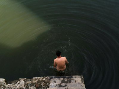 Un homme nage dans une piscine en plein air nudiste d'une banlieue de Pékin le 4 juin 2017 - FRED DUFOUR [AFP]