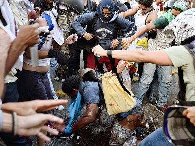 Des manifestants de l'opposition versent de l'essence sur un voleur présumé pendant une manifestation contre Maduro à Caracas le 20 mai 2017 - CARLOS BECERRA [AFP/Archives]