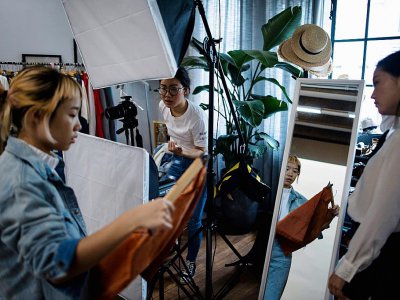 Les Chinoises Wang Ruhan (g) et Wang Houhou (c), photographient un modèle pour le lancement de leur boutique de mode en ligne, le 5 mai 2017 à Shanghai - Johannes EISELE [AFP]