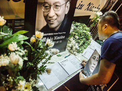 Un homme écrit un message et tient un portrait du dissident chinois Liu Xiaobo après le décès de celui-ci, devant le bureau de liaison chinois à Hong-Kong - Isaac Lawrence [AFP]