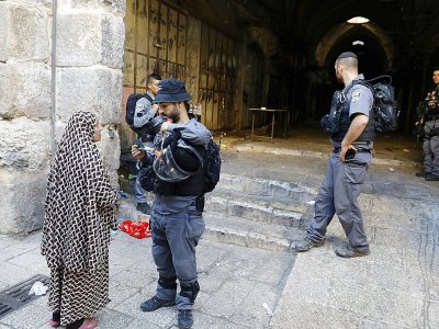 Un policier israélien contrôle les papiers d'idéntité d'une Palestinienne dans la Vieille ville de Jérusalem, le 16 juillet 2017 - MENAHEM KAHANA [AFP]