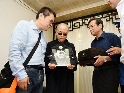 Photographie du Shenyang Municipal Information Office, montrant la femme du dissident chinois Liu Xiaobo, Liu Xia (c) et son frère, Liu Xiaoguang (L), recevant les cendres du défunt après son incinération, le 15 juillet 2015 à Shenyang - Handout [Shenyang Municipal Information Office/AFP]