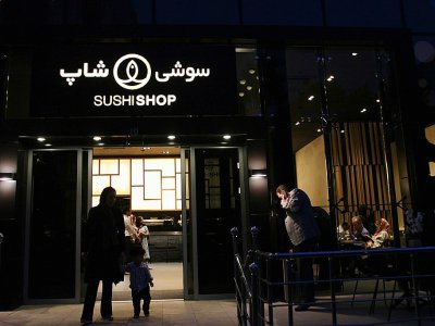 Des Iraniens devant un restaurant d'une chaine française de sushis récemment ouverte à Téhéran le 16 juillet 2017 - ATTA KENARE [AFP/Archives]
