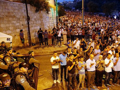 Des forces de sécurité israéliennes regardent des palestiniens prier à l'extérieur de l'esplanade des Mosquées à Jérusalem le 24 juillet 2017 - Ahmad GHARABLI [AFP]