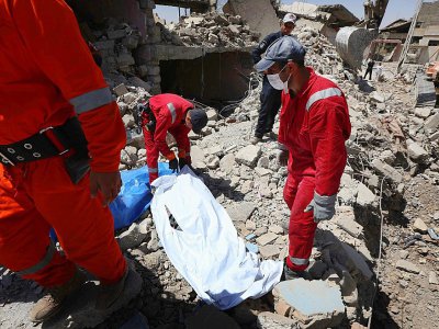 Des membres de la Défense civile recouvrent des corps retrouvés dans les ruines de maisons et d'immeubles, le 26 juillet 2017 à Mossoul - SAFIN HAMED [AFP]