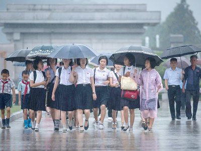 Des étudiantes marchent sous la pluie pour aller se recueillir devant le mausolée du fondateur du régime Kim Il-Sung, le 27 juillet 2017 à Pyongyang - Ed JONES [AFP]