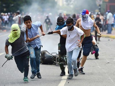 Militants anti-gouvernement au Venezuela tirent derrière eux une moto de la police brûlée après l'explosion d'un engin lors d'une manifestation contre l'élection de l'Assemblée constituante, à Caracas le 30 juillet 2017 - Ronaldo SCHEMIDT [AFP]