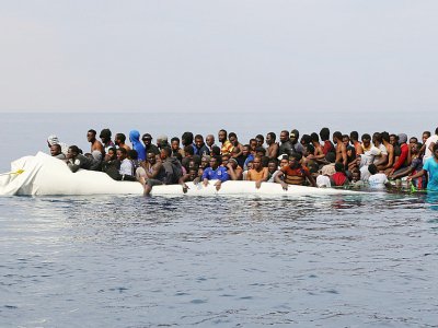 Tandis que leur canot coule, des migrants attendent d'être secourus au large des côtes de Zawiyah en Libye, à l'est de Tripoli, le 20 mars 2017 - Abdullah ELGAMOUDI [AFP/Archives]
