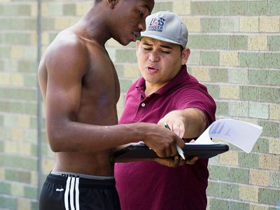 Teofilo Chavez (g), 17 ans, remplit des documents avec l'aide d'Elvis Garcia Callejas, entraîneur d'un groupe de football amateur et avocat pour Catholic Charities, 22 juillet 2017 à New York, dans le Bronx - DON EMMERT [AFP]