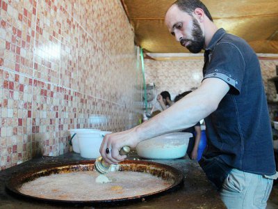 Un syrien prépare un plat dans le restaurant "Les mets damascènes Ibad al-Rahmane", dans la ville rebelle d'Idleb, en Syrie, le 19 juillet 2017 - Omar haj kadour [AFP]