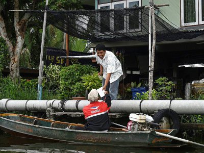 Nopadol, postier, distribue des lettres et colis aux habitants vivant sur les bords d'un canal dans la province de Bang Khun Thian, près de Bangkok en Thaïlande, le 17 juillet 2017 - Lillian SUWANRUMPHA [AFP]