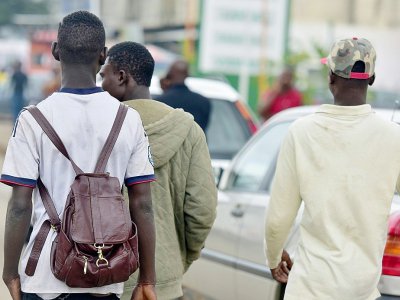 De jeunes hommes marchent dans le quartier populaire d'Abobo, à Abidjan, le 3 août 2017 - ISSOUF SANOGO [AFP]