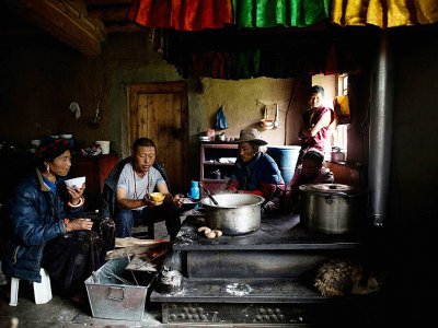 Une femme et sa famille prennent leur petit-déjeuner, constitué notamment de thé et de beurre de yak, le 28 mai 2017, à Zhaba, dans la vallée du fleuve Yalong, dans la province chinoise du Sichuan - Johannes EISELE [AFP]