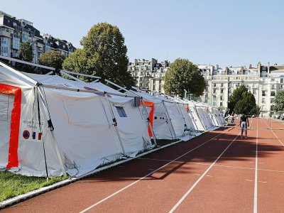 Des migrants jouent au foot devant des tentes installées par la Sécurité civile sur un terrain de sport dépendant de l'Université Panthéon-Assas le 22 août 2017 - PATRICK KOVARIK [AFP]