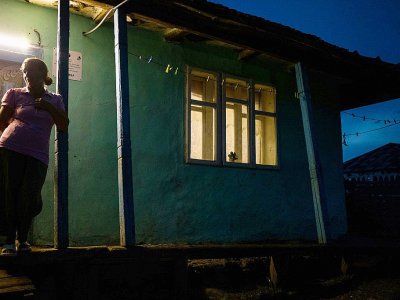 Une femme sur le seuil de sa maison après l'installation d'un panneau solaire qui lui fournit l'électricité, le 25 juillet 2017 à Gorbanesti, en Roumanie - ANDREI PUNGOVSCHI [AFP]