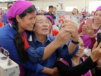 Le Premier ministrre cambodgien Hun Sen fait des selfies avec des ouvrières d'une usine qu'il visite dans les environs de Phnom Penh le 30 août 2017 - STR [AFP/Archives]