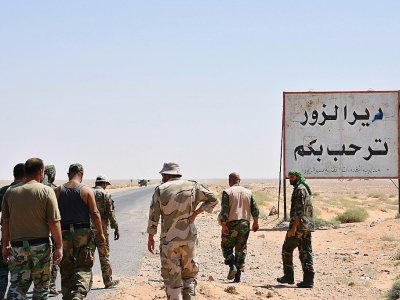 Des membres des forces gouvernementales à l'entrée de Deir Ezzor, le 3 septembre 2017, devant le panneau d'entrée dans la ville: "Bienvenue à Deir Ezzor" - George OURFALIAN [AFP]