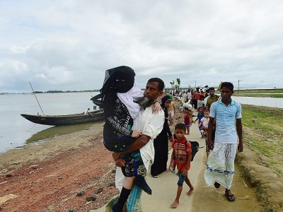 Des réfugiés Rohingyas qui portent un parent âgé arrivent de Birmanie après avoir traversé la rivière Naf de la ville de Teknaf au Bangladesh le 12 septembre 2017 - MUNIR UZ ZAMAN [AFP]