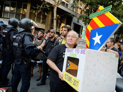 Une personne porte une urne symbolique face à des policiers espagnols en soutien au référendum catalan. Le 20 septembre 2017. - Josep LAGO [AFP]
