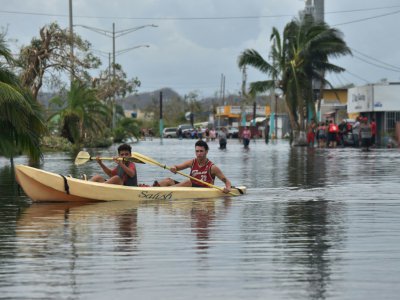 Des habitants utilisent un kayak pour se déplacer dans leur rue inondée, à Juana Matos, sur lîle de Porto Rico, le 21 septembre 2017 après le passage de l'ouragan Maria - HECTOR RETAMAL [AFP]