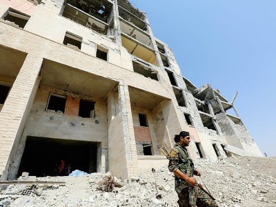 Un combattant des forces démocratiques syriennes (FDS) devant un immeuble détruit, le 21 septembre 2017 à Raqa - Delil souleiman [AFP]