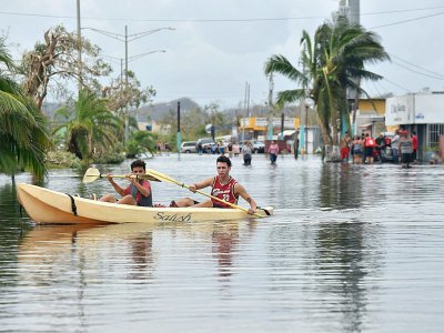 Des habitants utilisent un kayak pour se déplacer dans leur rue inondée, à Juana Matos, sur lîle de Porto Rico, le 21 septembre 2017 après le passage de l'ouragan Maria - HECTOR RETAMAL [AFP]
