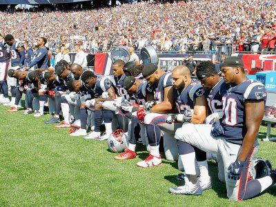 Des joueurs des New England Patriots, agenouillés au bord du terrain quelques heures après que Donald Trump a proposé de boycotter les équipes dont les joueurs "manquent de respect" à l'Amérique, le 24 septembre 2017 à Foxboro - Jim Rogash [Getty/AFP]