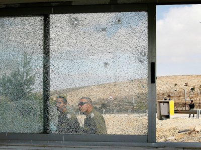 Des forces de sécurité israéliennes passent devant les vitres brisées du poste de contrôle de Har Adar, le 26 septembre 2017 - Menahem KAHANA [AFP]