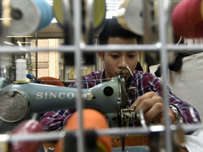 Un artisan à l'oeuvre de un atelier qui fabrique des qipao, robe moulante traditionnelle chinoise, le 29 août 2017 - SAM YEH [AFP]