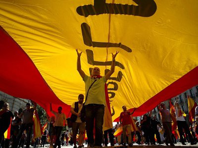 Des manifestants protestent sous un drapeau espagnol contre l'indépendance de la Catalogne, à Barcelone, le 8 octobre 2017 - JORGE GUERRERO [AFP]