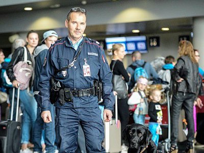 Thierry, contrôleur des douanes, pose avec Goran, chien renifleur de billets, à l'aéroport de Mulhouse le 10 octobre 2017 - SEBASTIEN BOZON [AFP]