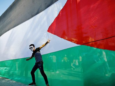 Un jeune homme pose devant le drapeau palestinien le 12 octobre 2017 dans la ville de Gaza - MOHAMMED ABED [AFP/Archives]