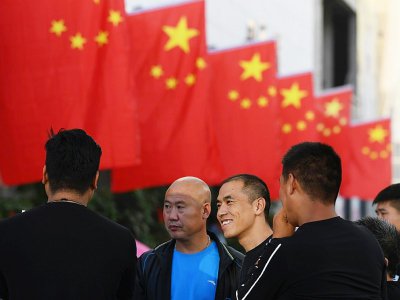 Des employés discutent après avoir installé des drapeaux de la Chine devant un centre commercial à Lankao, dans la province du Henan (centre), le 28 septembre 2017 - GREG BAKER [AFP/Archives]