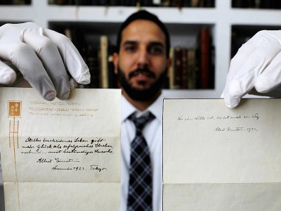 Le propriétaire de la maison d'enchères Winner's à Jérusalem tient deux notes écrites par Albert Einstein, le 19 octobre 2017 - MENAHEM KAHANA [AFP]