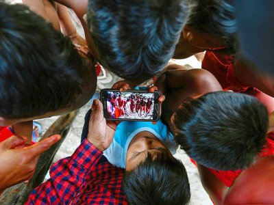 Des enfants de la tribu Waiapi regardent sur un smartphone une vidéo d'une danse traditionnelle Waiapi, dans leur village de Manilha le 12 octobre 2017 - Apu Gomes [AFP]