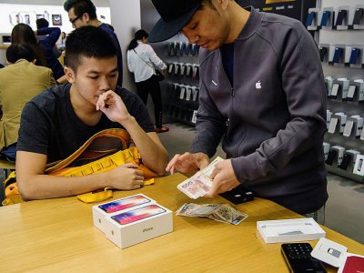 Un homme achète deux iPhone X dans une boutique Apple, le 3 novembre 2017 à Hong Kong - ANTHONY WALLACE [AFP]