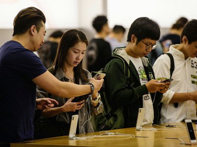 Des personnes regardent l'iPhone X en vente dans une boutique Apple, le 3 novembre 2017 à Hong Kong - ANTHONY WALLACE [AFP]