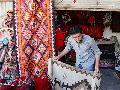 Un vendeur montre des tapis traditionnels dans une échoppe du marché de Hilla, le 12 octobre 2017 en Irak - SABAH ARAR [AFP]