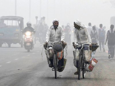 Des Indiens à vélo, un jour de forte pollution à New Delhi, le 7 novembre 2017 - PRAKASH SINGH [AFP]