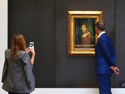 Un couple regarde le tableau "La Belle Ferronière" de Léonard De Vinci au Louvre Abou Dhabi lors d'une visite organisée pour les médias le 6 novembre 2017 - GIUSEPPE CACACE [AFP]