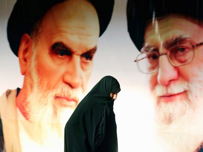 Photo d'une Iranienne passant devant un portrait du guide suprême, l'Ayatollah Ali Khamenei (D), et du fondateur de la République islamique, l'Ayatollah Ruhollah Khomeini (G), le 1er février 2015 près de Téhéran - ATTA KENARE [AFP/Archives]