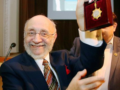 Samuel Bak, peintre et survivant de l'Holocauste, brandit une médaille lors de l'inauguration de son musée à Vilnius, le 20 novembre 2017 - Petras Malukas [AFP]